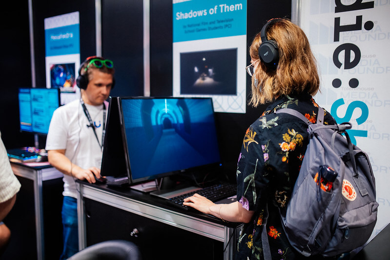 An image of people playing games displayed as part of the Indie Showcase from a previous year of the conference.